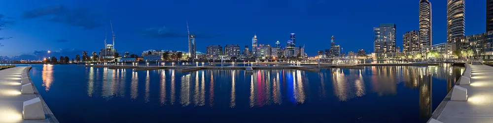 ヨットが係留されたドックランズの水辺と、その背後に建つ高層ビル群